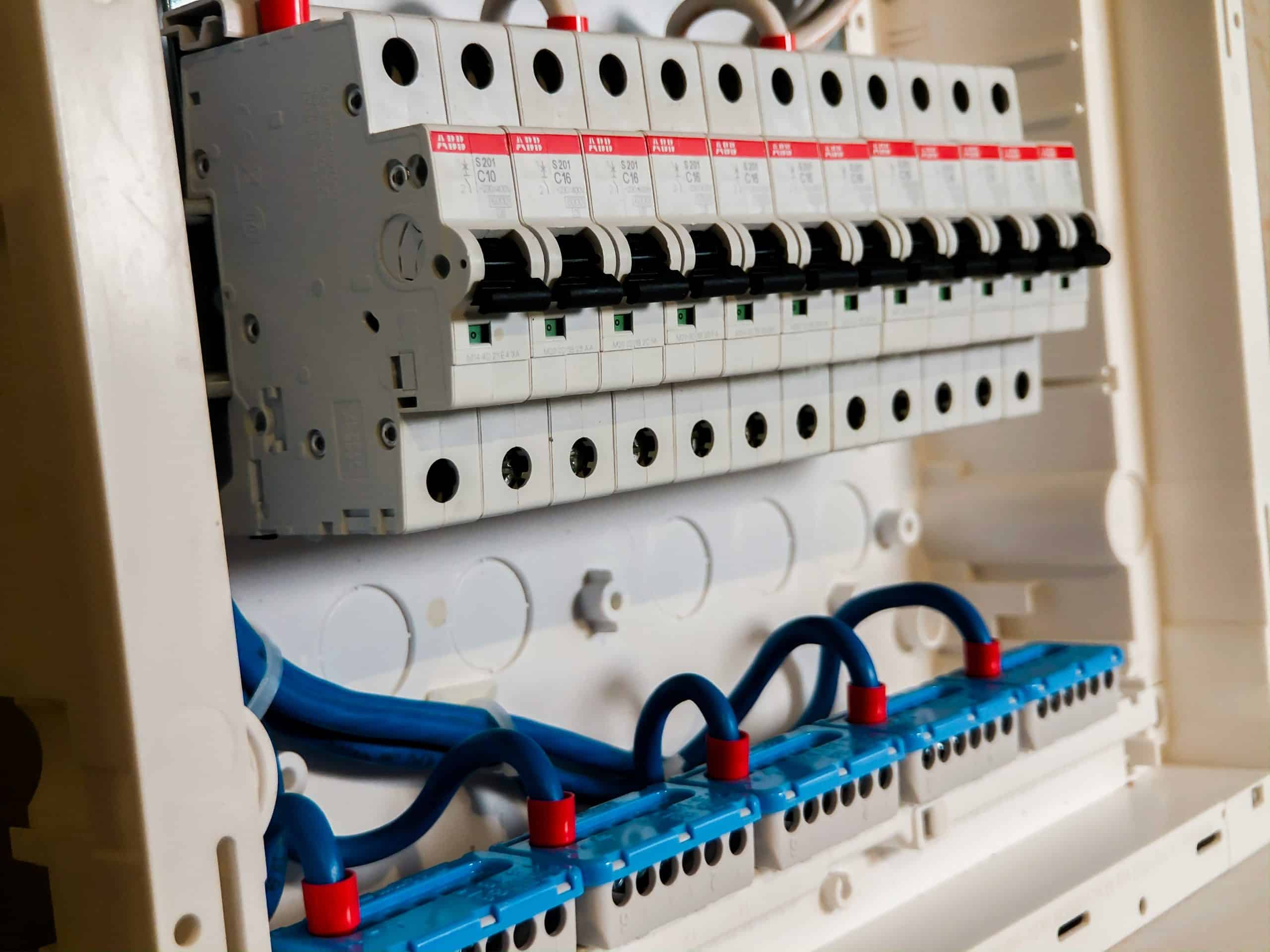 Close-up view of an electrical breaker panel with circuit switches and blue wiring.